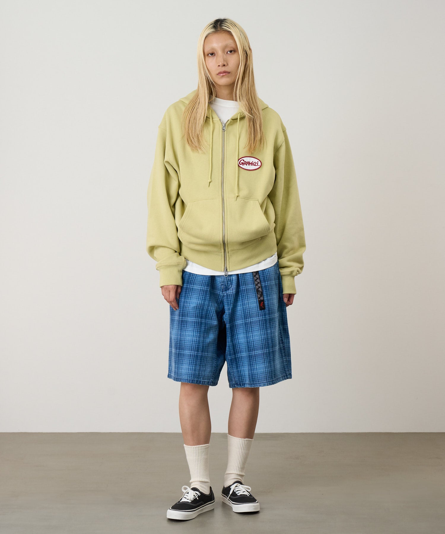 Front view of a model wearing Gramicci Oval Patch Zip Hooded Sweatshirt Lime with a soft fleece fabric and full-zip design for everyday wear.