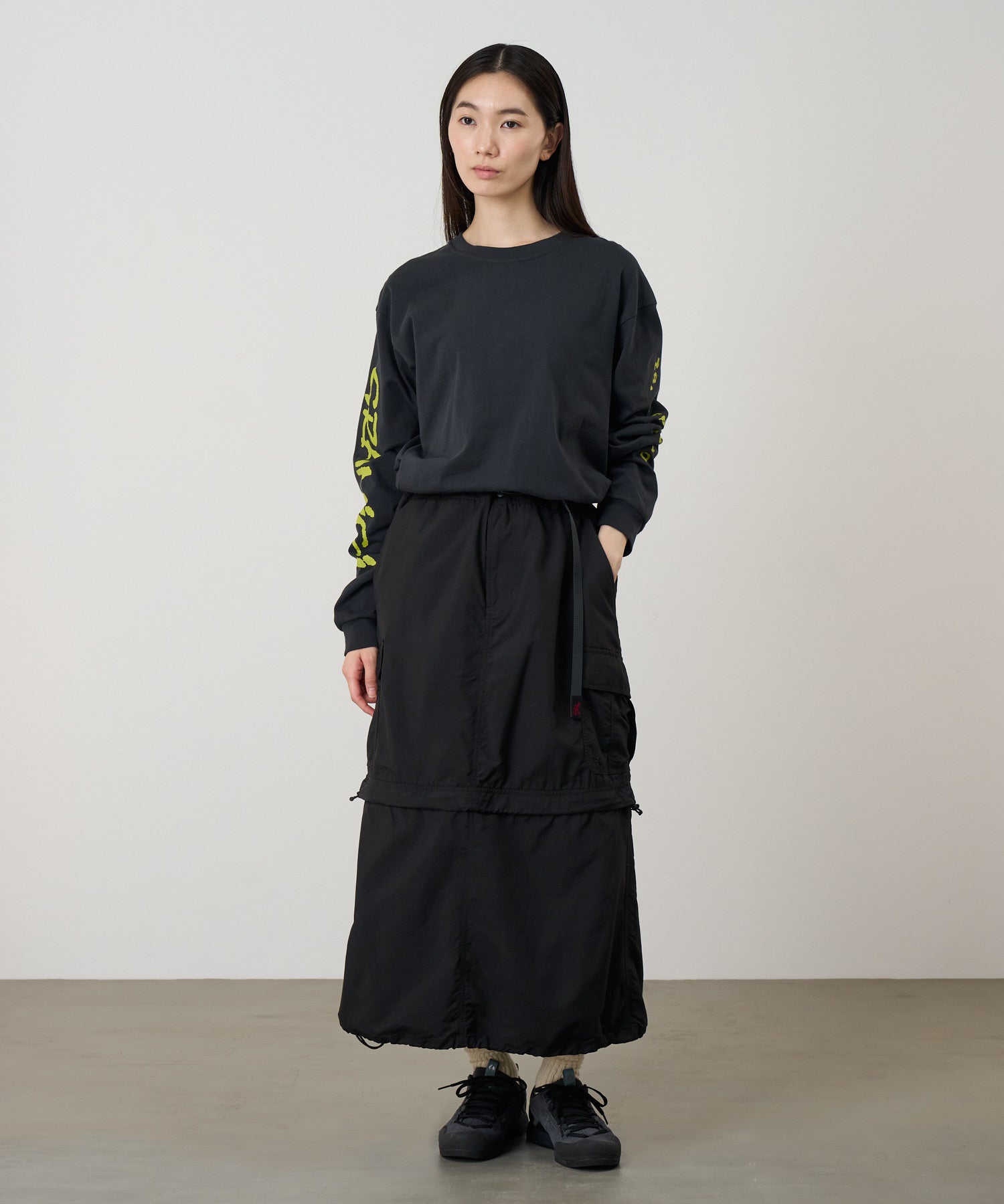 Model wearing Gramicci Convertible Cargo Skirt Black in eco cotton with utility cargo pockets, adjustable fit and versatile everyday style.